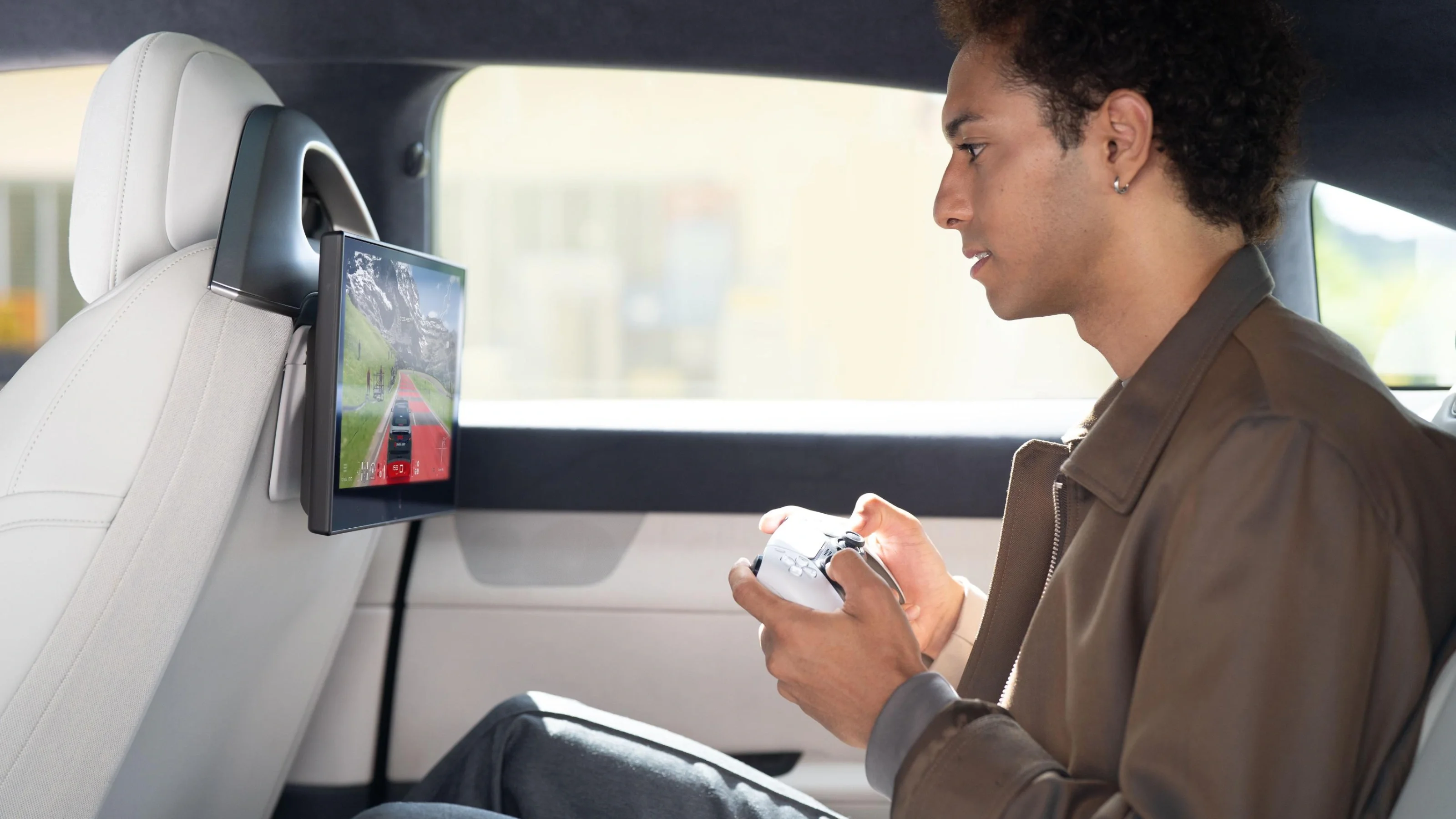 Imagen que muestra a un pasajero en el asiento trasero de un auto jugando un videojuego de PlayStation en una pantalla