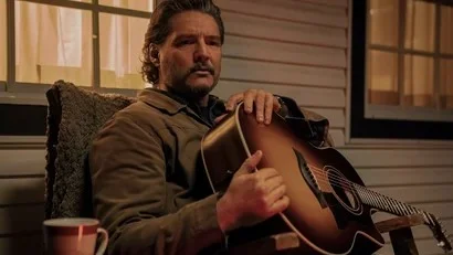 Pedro Pascal como Joel en The Last of Us, sosteniendo una guitarra