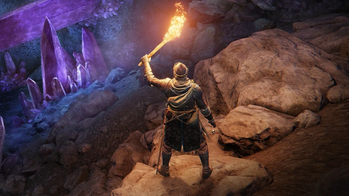 Elden Ring screenshot showing a knight holding up a torch in an area full of giant gem-like looking rocks