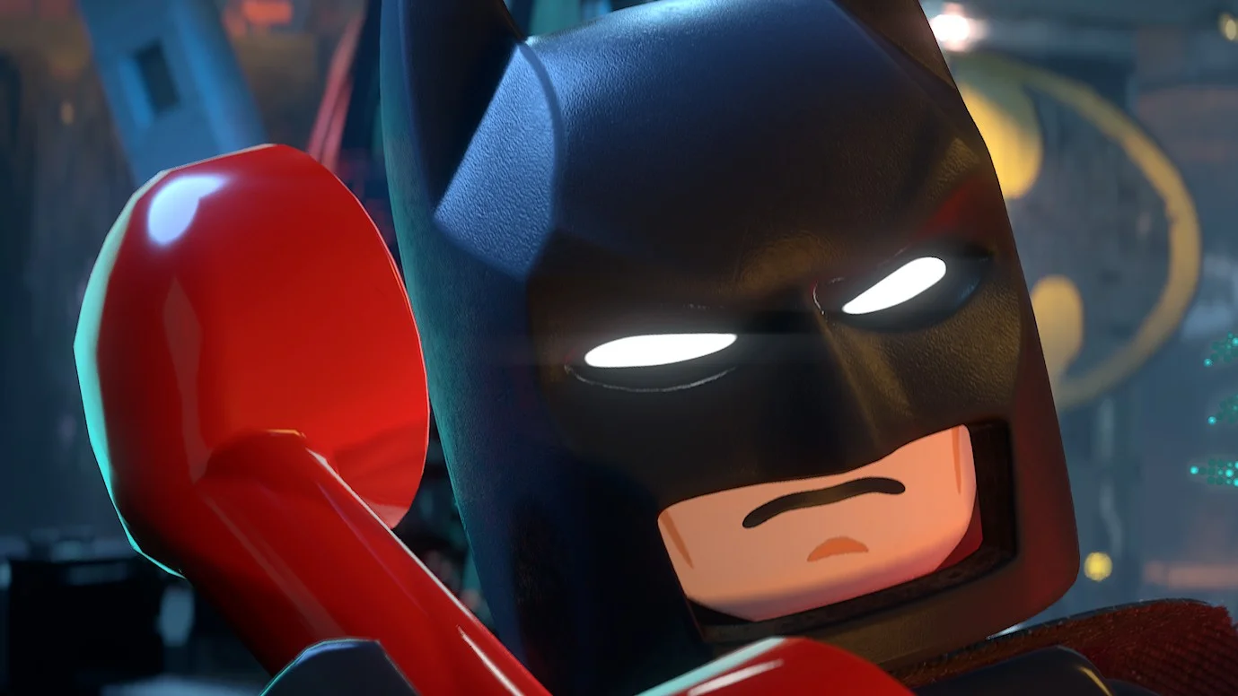 Captura de pantalla de Lego Batman Legacy of the Dark Knight mostrando a Batman en su Batcueva hablando por un teléfono rojo